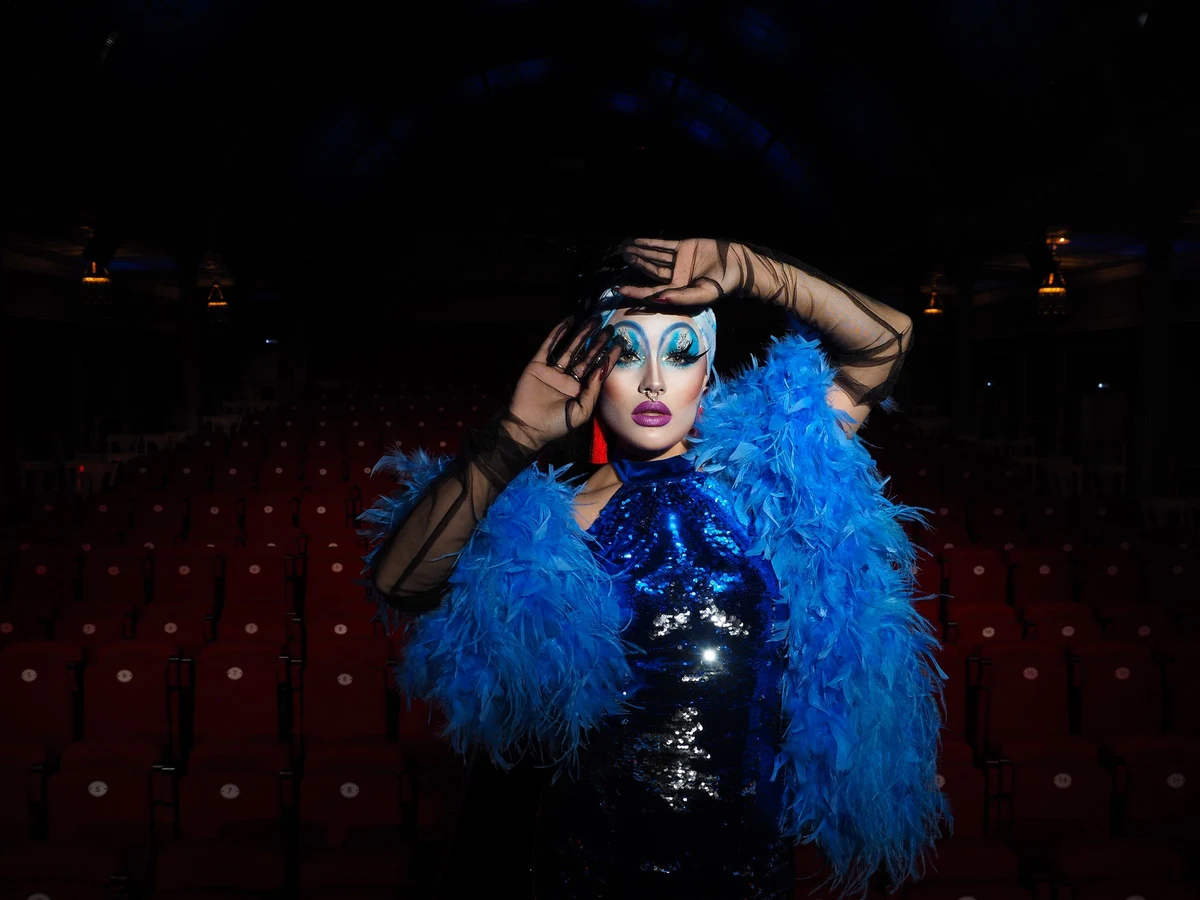A performer in an elaborate feathered costume and dramatic stage makeup in a theatre auditorium (representative photograph, not this venue's own cast)