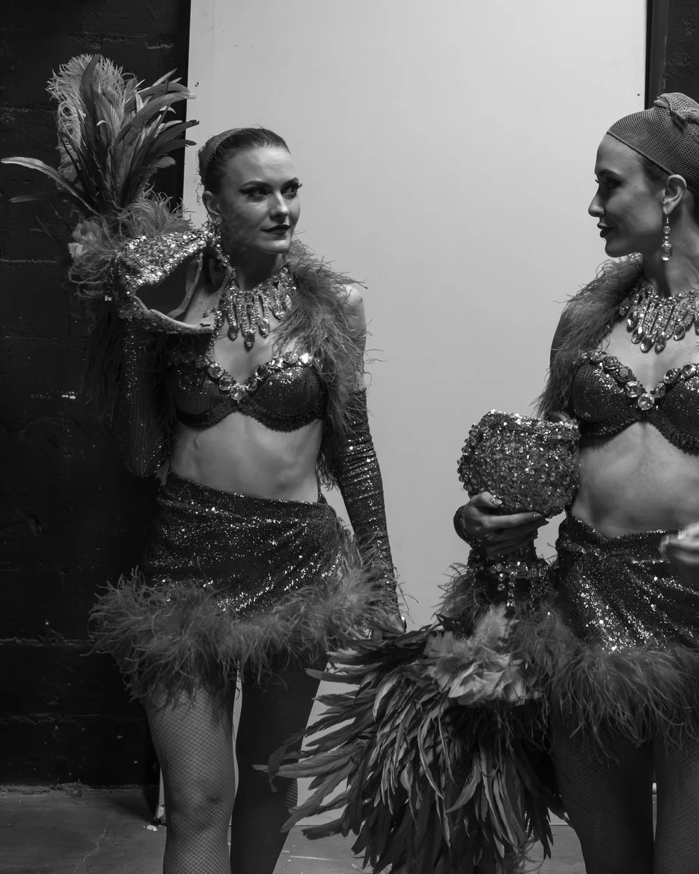 Black-and-white backstage photograph of two cabaret dancers in sparkling, feathered costumes (representative photograph, not Avanspettacolo Venezia's own cast)