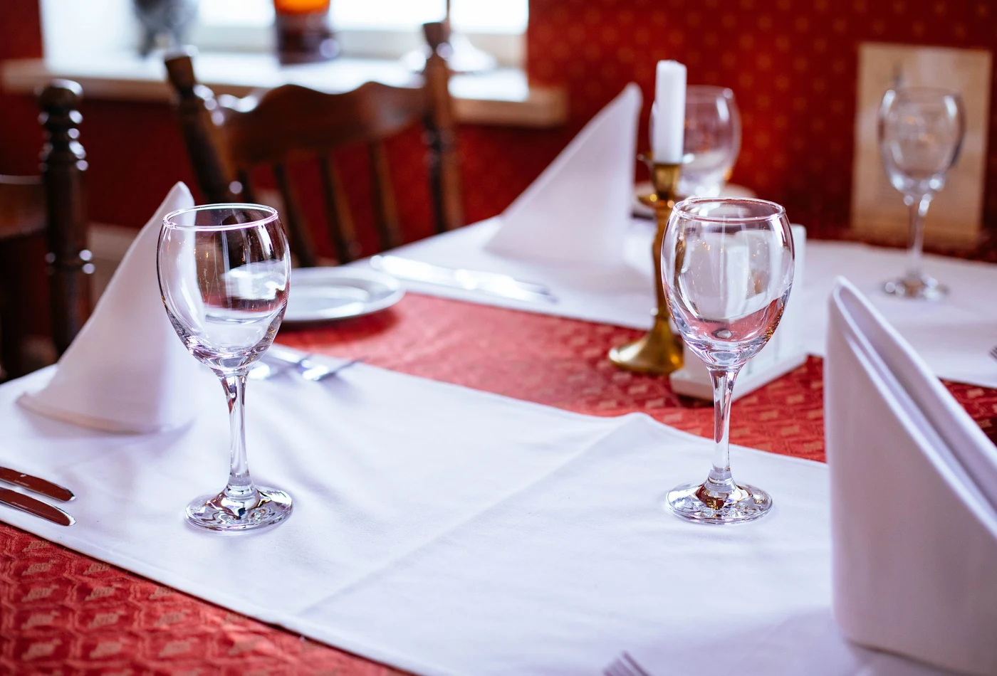 A set restaurant table with wine glasses, white linen and a lit candle (representative photograph, not this venue's own dining room)